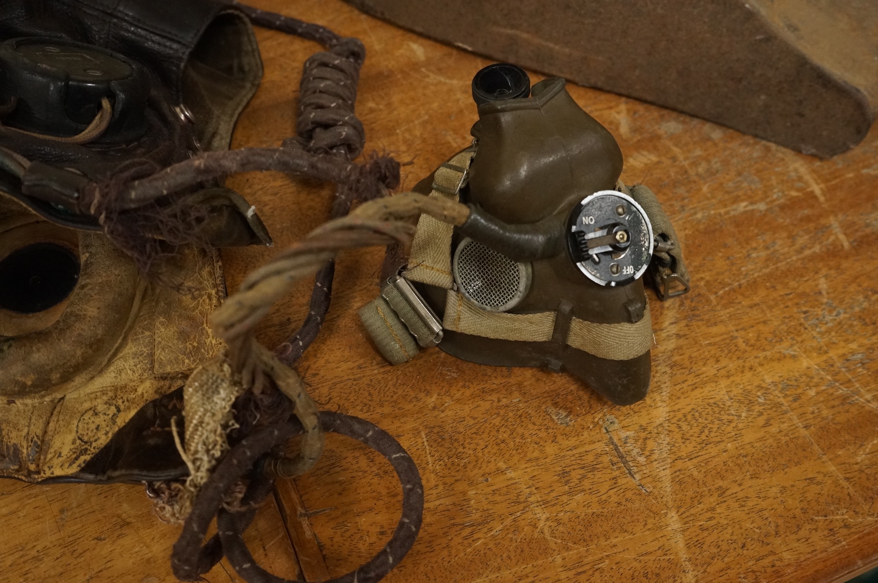 A WWII RAF Air Ministry aviator’s leather head-gear, with built-in padded headphones, oxygen mask with microphone and other electrics incorporated into it, marked with a crown and ‘AM 10A/13466’ to one earpiece, together